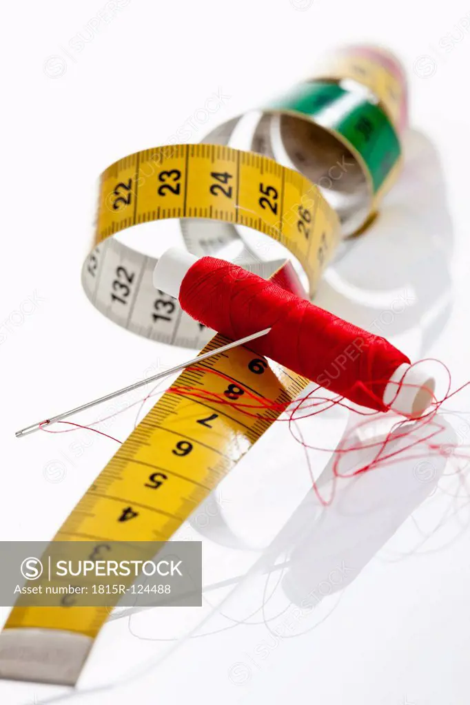 Needle, thread and measure tape on white background, close up