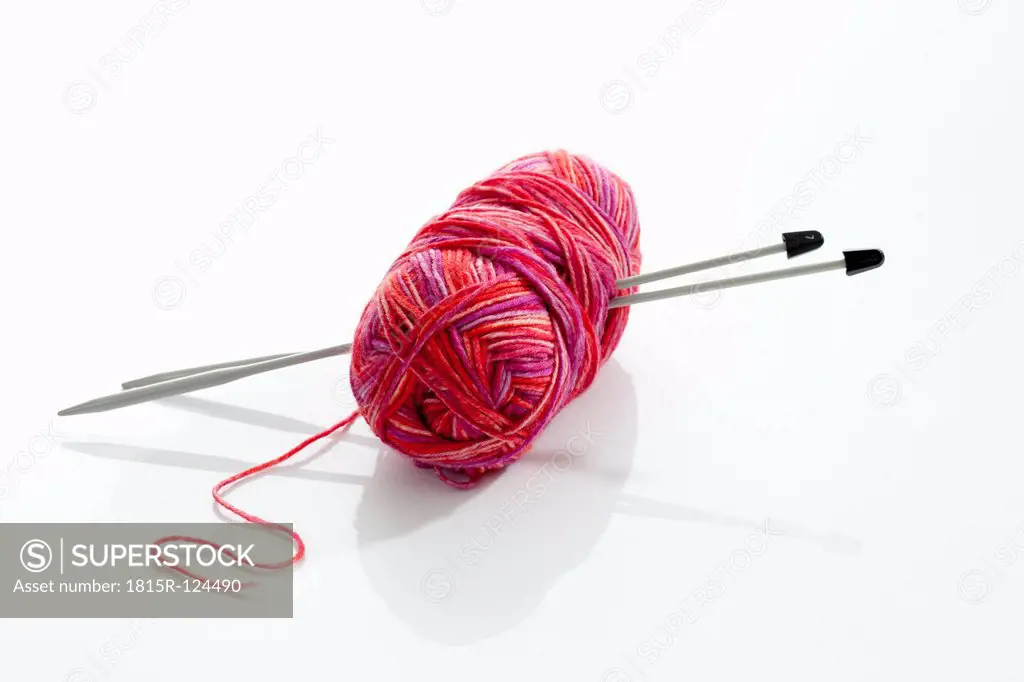 Yarn with knitting needles on white background, close up