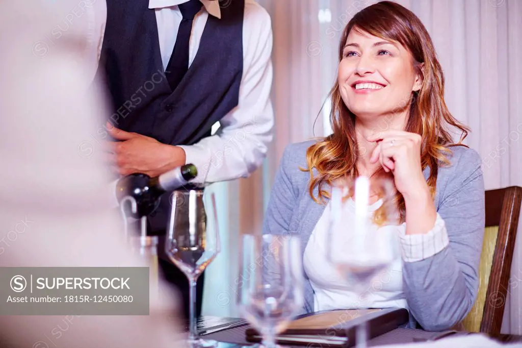 Waiter pouring wine for business associates at hotel restaurant