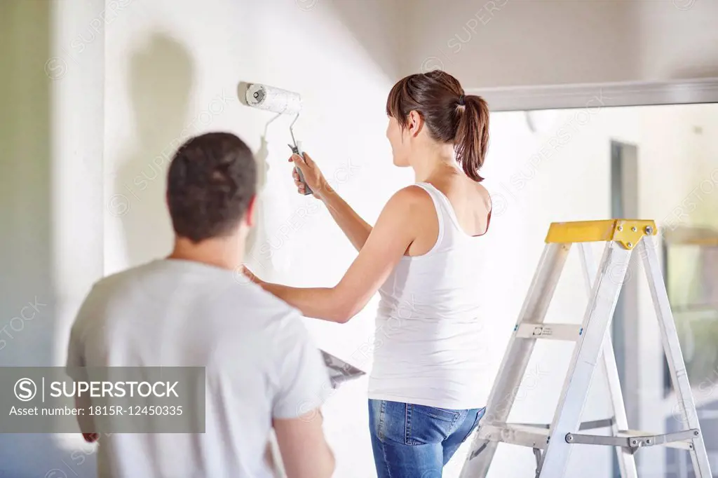 Couple painting the wall in new home