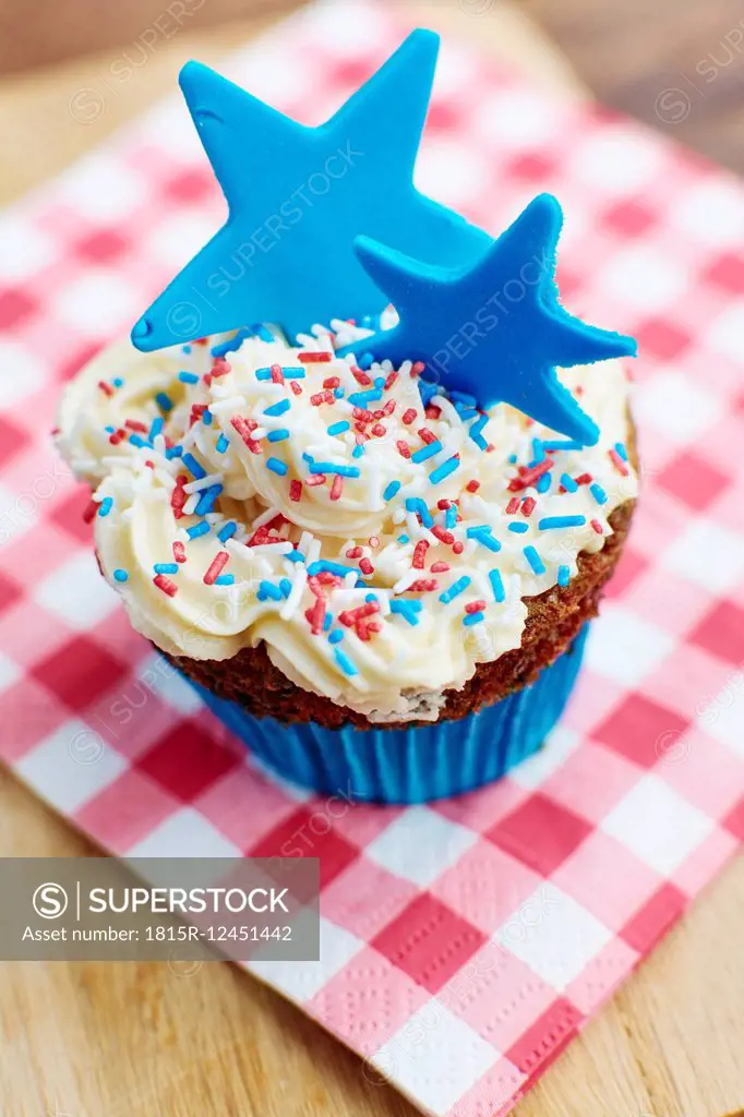 Cupcakes with a white frosting, colorful sprinkles and a blue star made from fondant