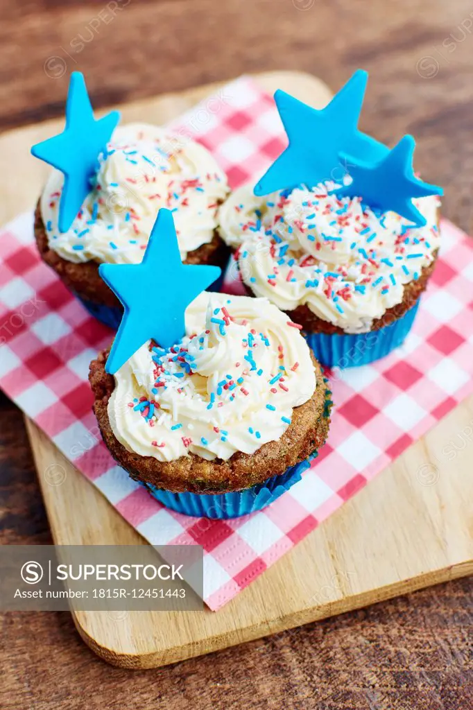 Cupcakes with a white frosting, colorful sprinkles and a blue star made from fondant