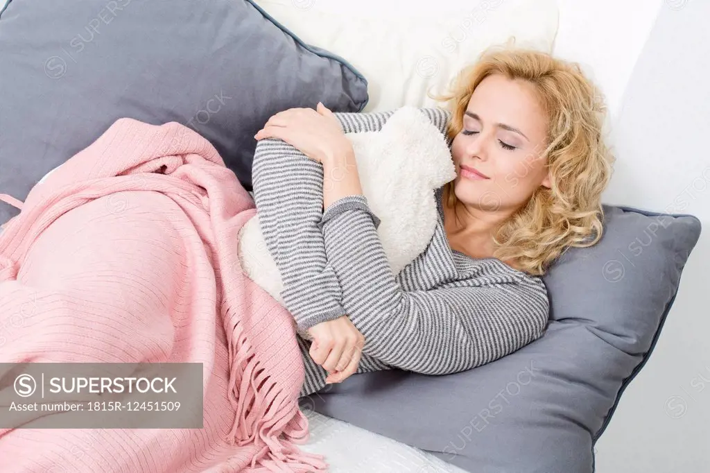 Woman lying on couch with hot water bottle