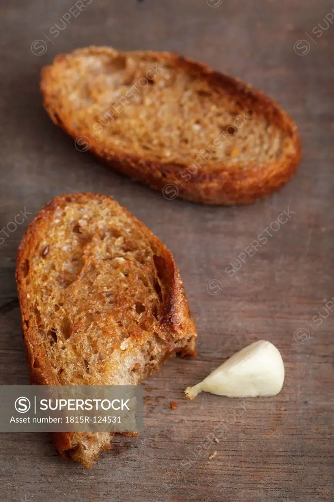 Roasted bread with garlic on wooden table, close up