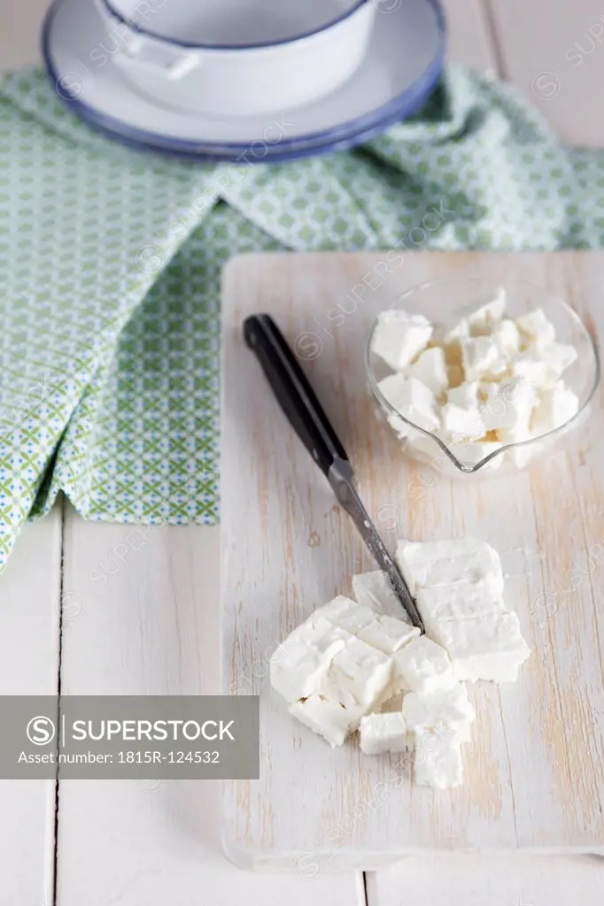 Feta cheese with knife on chopping board, close up