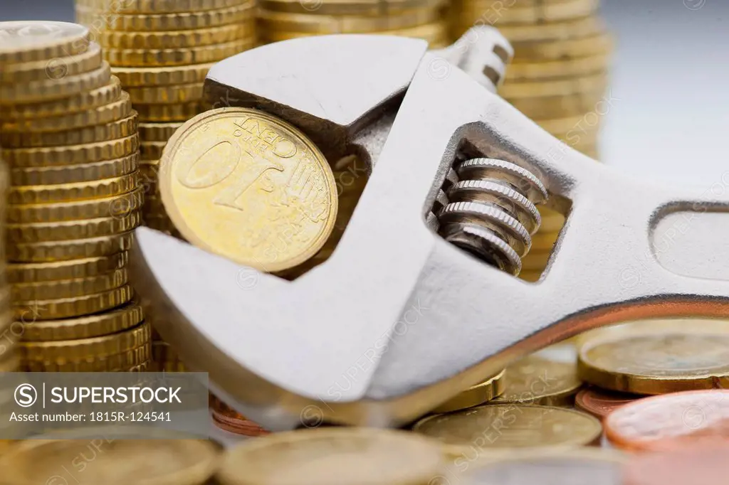 Stack of Euro coins and Ten cent coin held within adjustable wrench