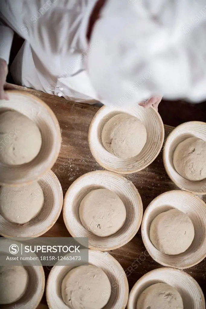 Female baker preparing ceramic bowls for baking bread