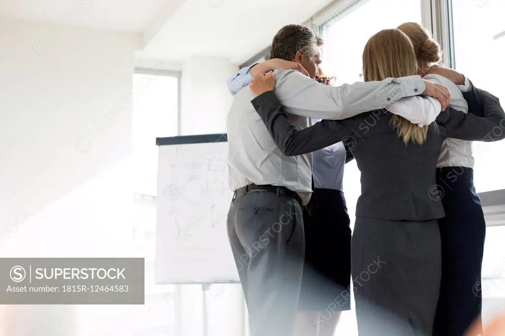Business people standing in circle, arms around