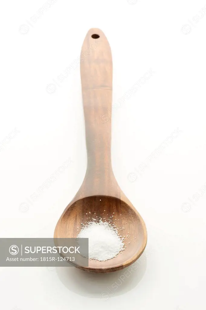 Salt in wooden spoon on white background, close up