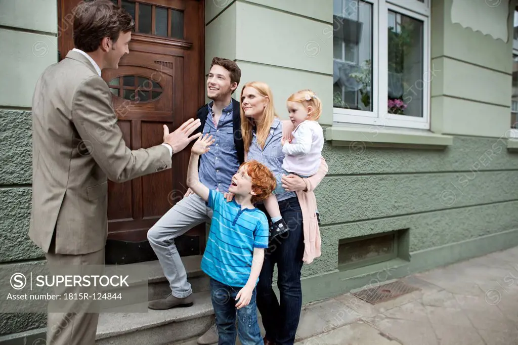 Germany, Duesseldorf, Boy giving high five to estate agent and family standing in background