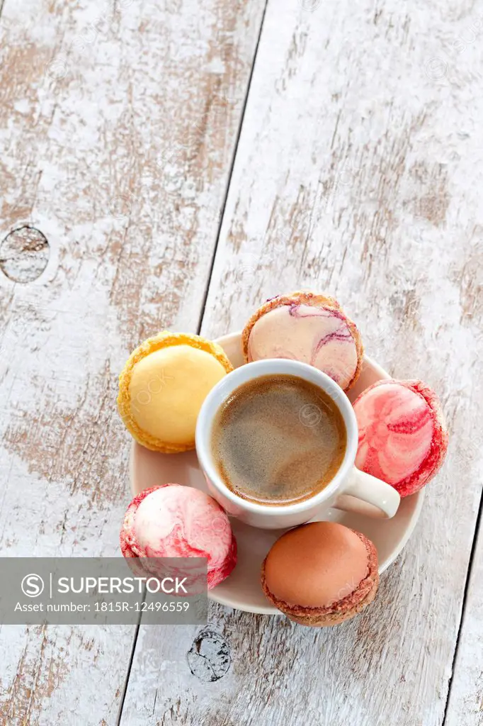 Cup of coffee with five macarons on saucer