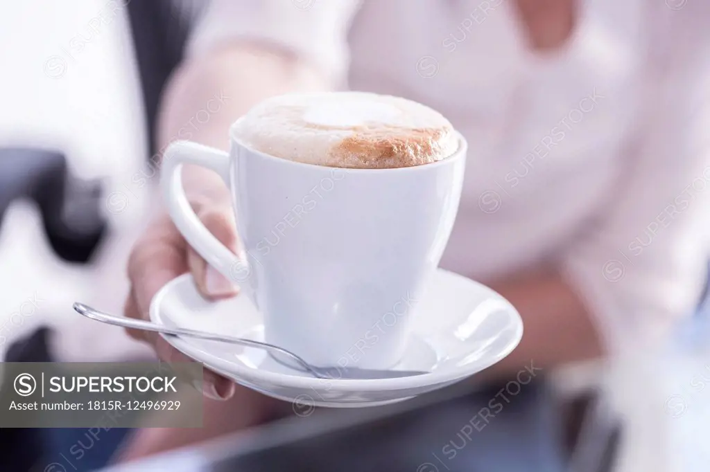 A woman offering cappuccino