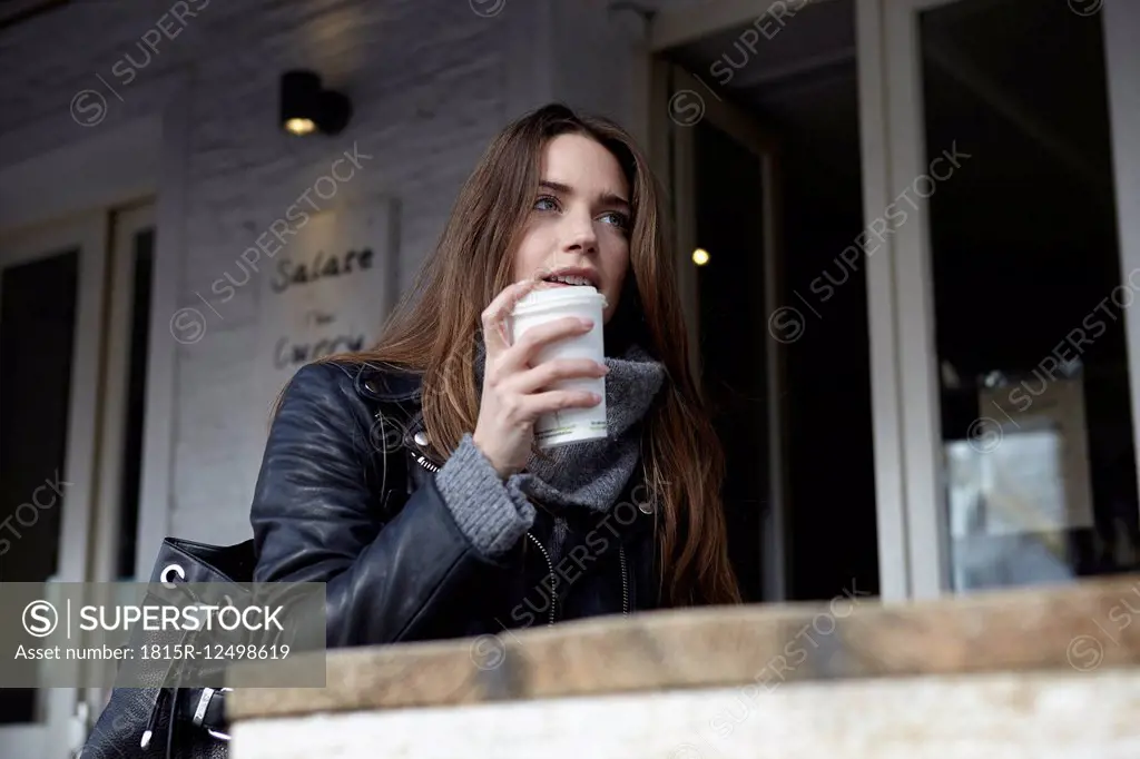 Germany, Dusseldorf, Young woman with coffee sitting outdoor