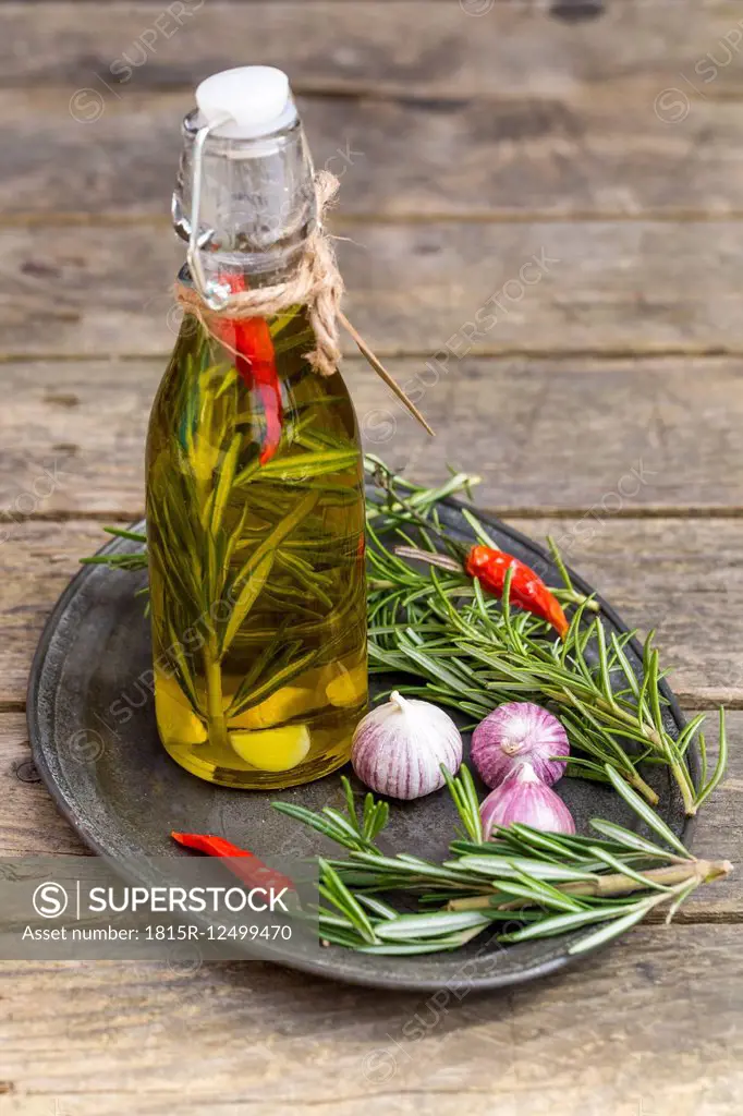 Rosemary oil in bottle, garlic, rosmary and chilli peppers on plate