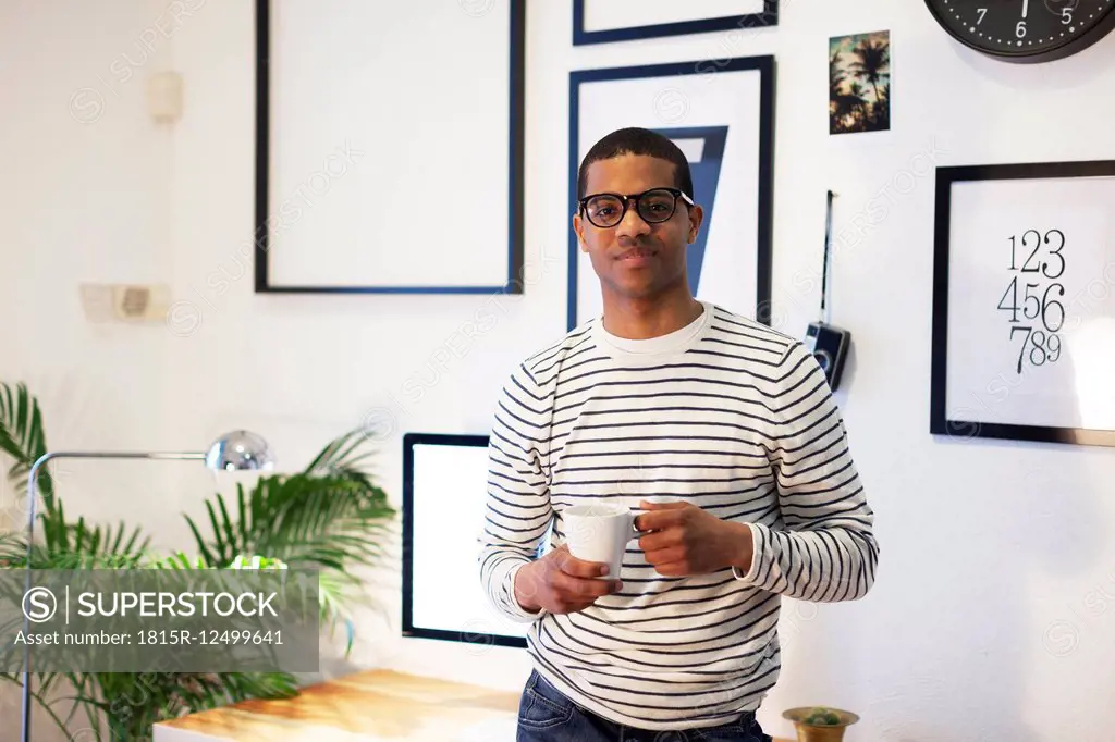 Young creative man having coffee break at his home office