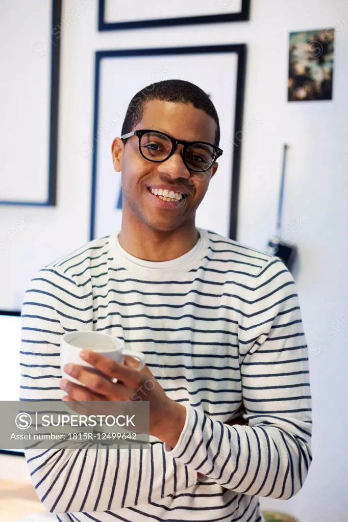 Portrait of smiling young man having a coffee break at his home office