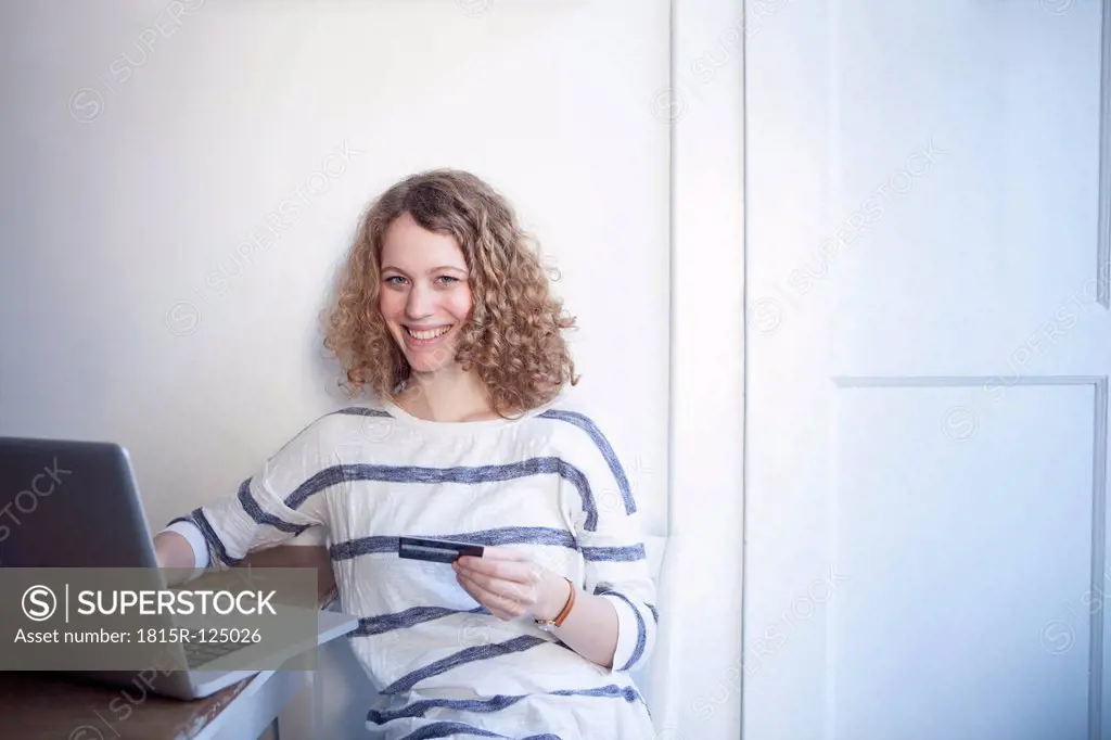 Germany, Bavaria, Munich, Young woman shopping online from home with laptop and credit card