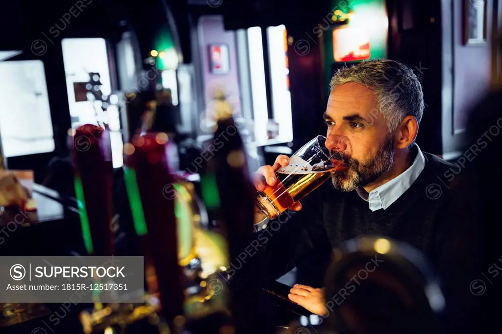 Man sitting at counter of a pub drinking beer