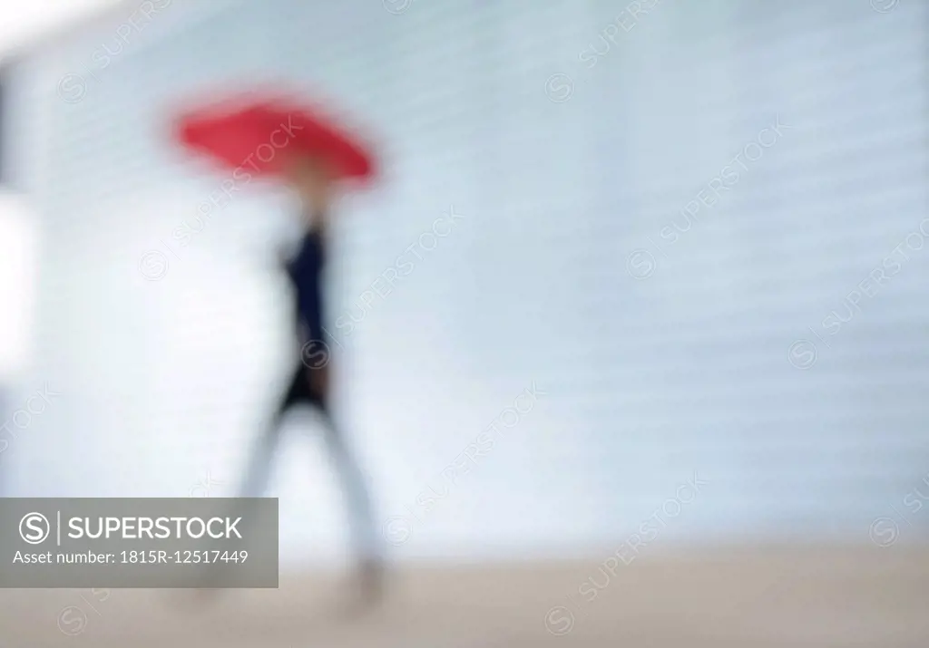 Businesswoman walking with red umbrella