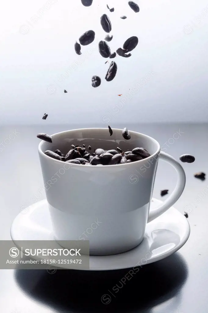 Coffee beans falling in a white coffee cup