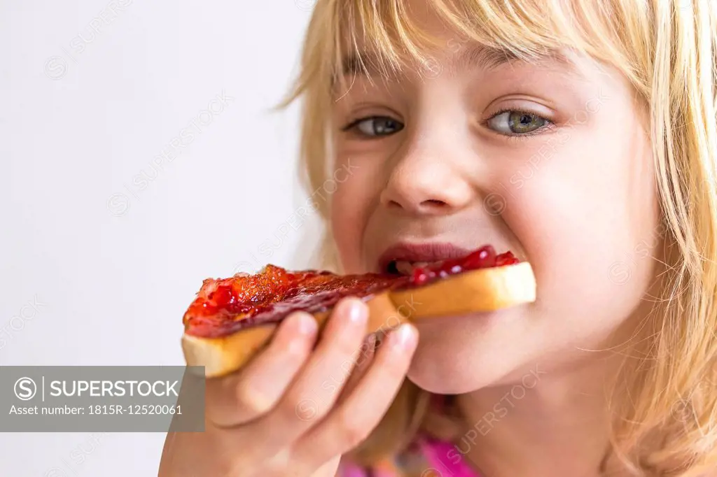 Portrait of blond girl eating bread with jam