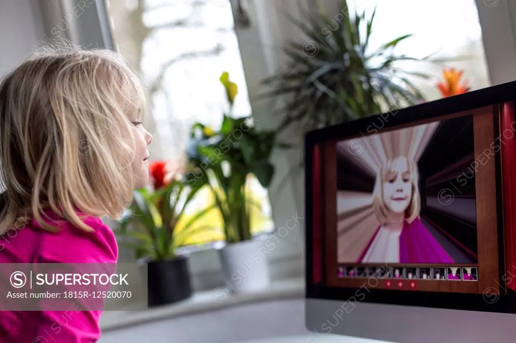 Little girl watching herself on flatscreen monitor