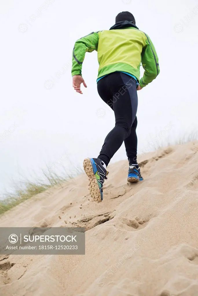 Spain, Galicia, Valdovino, man running up a dune on the beach