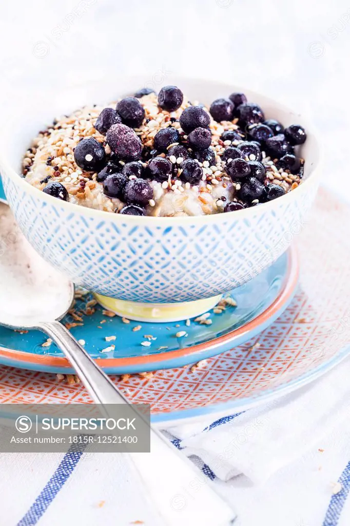 Vegan superfood breakfast with porridge, almond milk, blueberries and roasted quinoa