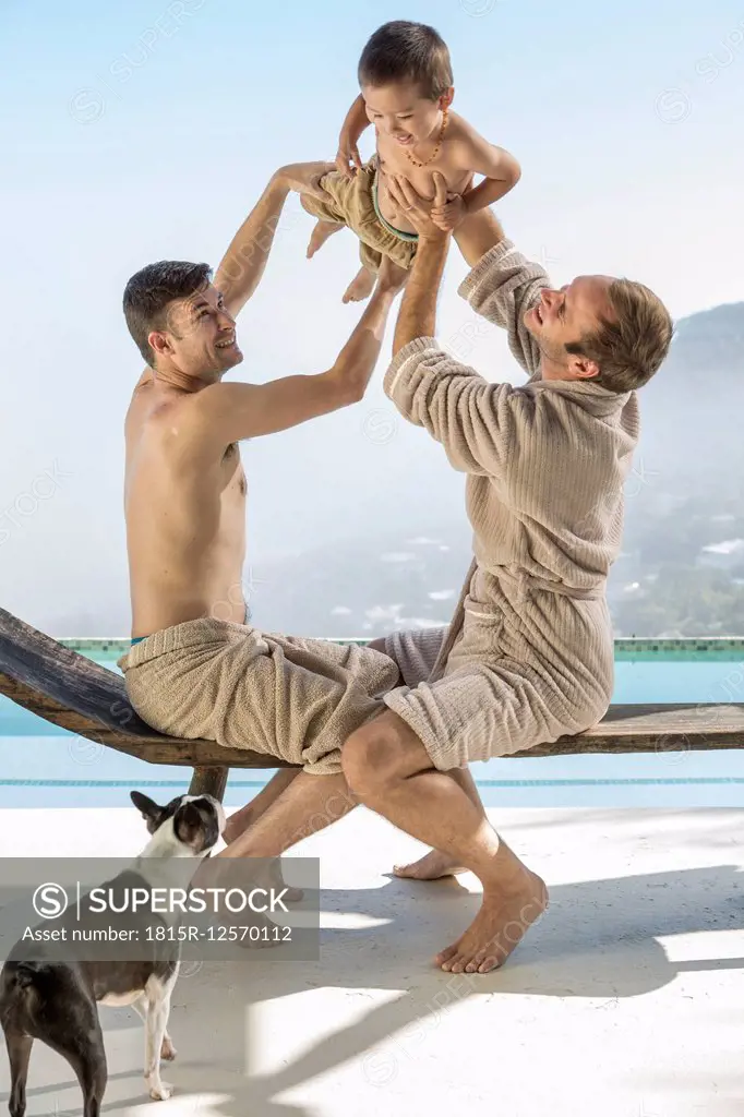 Gay couple playing with baby at the poolside