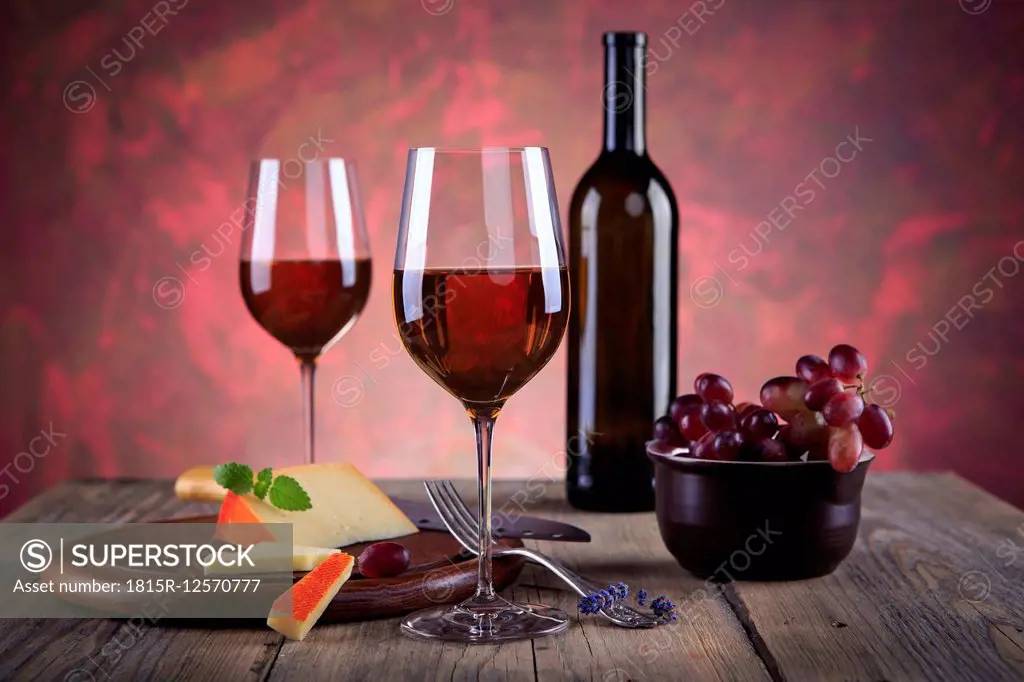 Still life with wine bottle, wine glasses, cheese and grapes