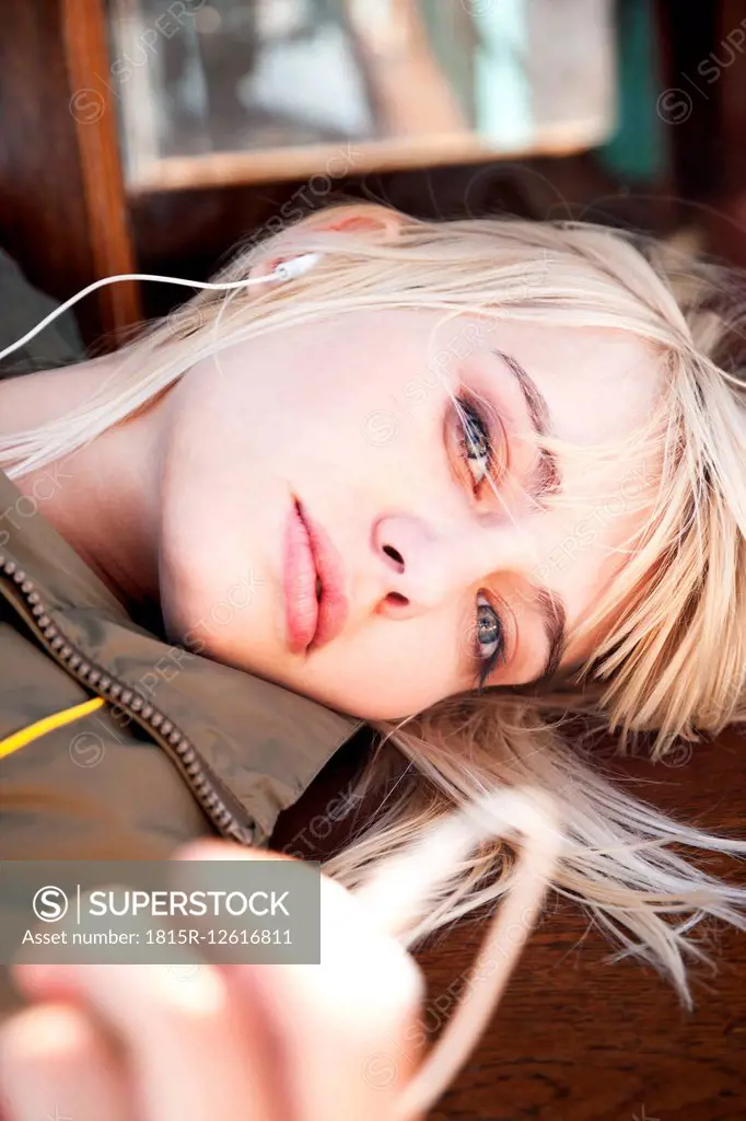 Relaxed young woman lying on a bench listening to music