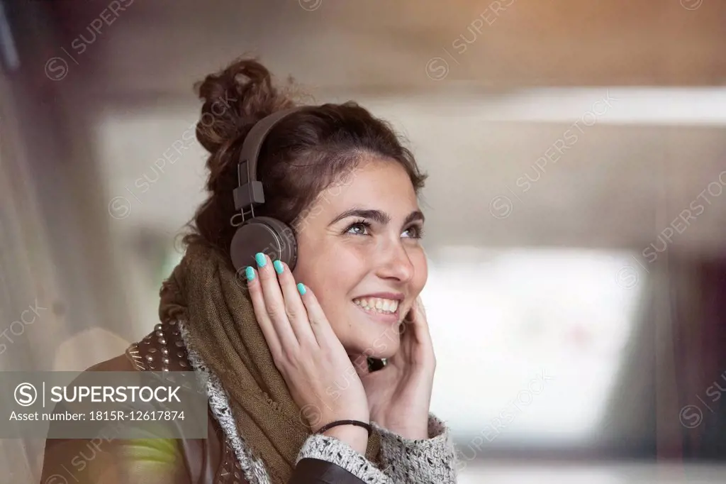 Portrait of smiling young woman hearing music with headphones