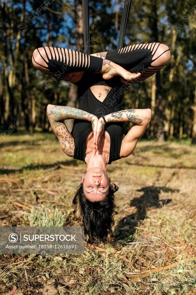 Woman practicing aerial yoga outdoors