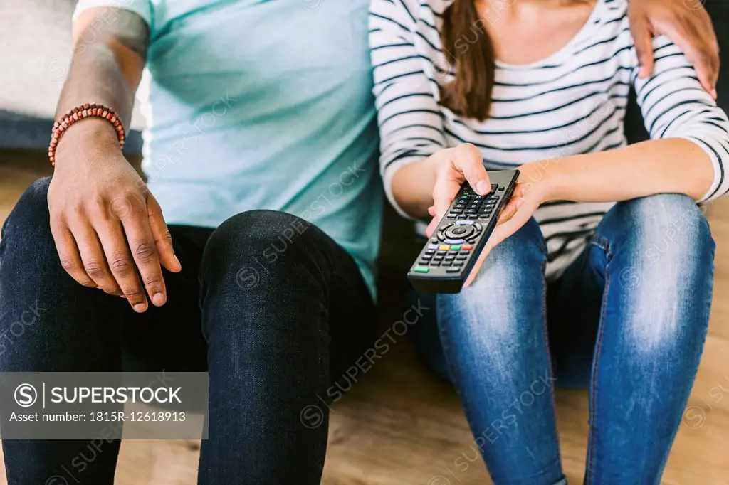 Young couple sitting on couch, holding remote control