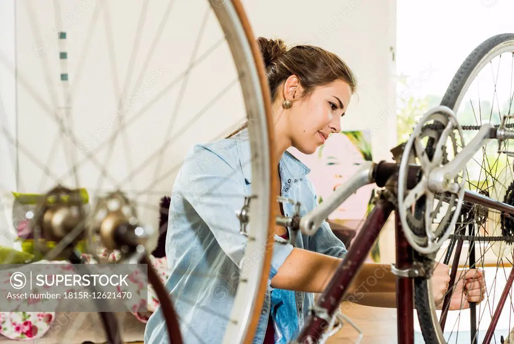Young woman at home repairing her bicycle