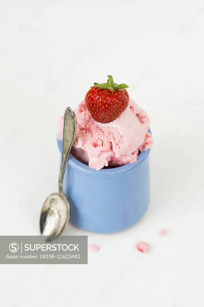 Strawberry ice cream in blue cup, spoon