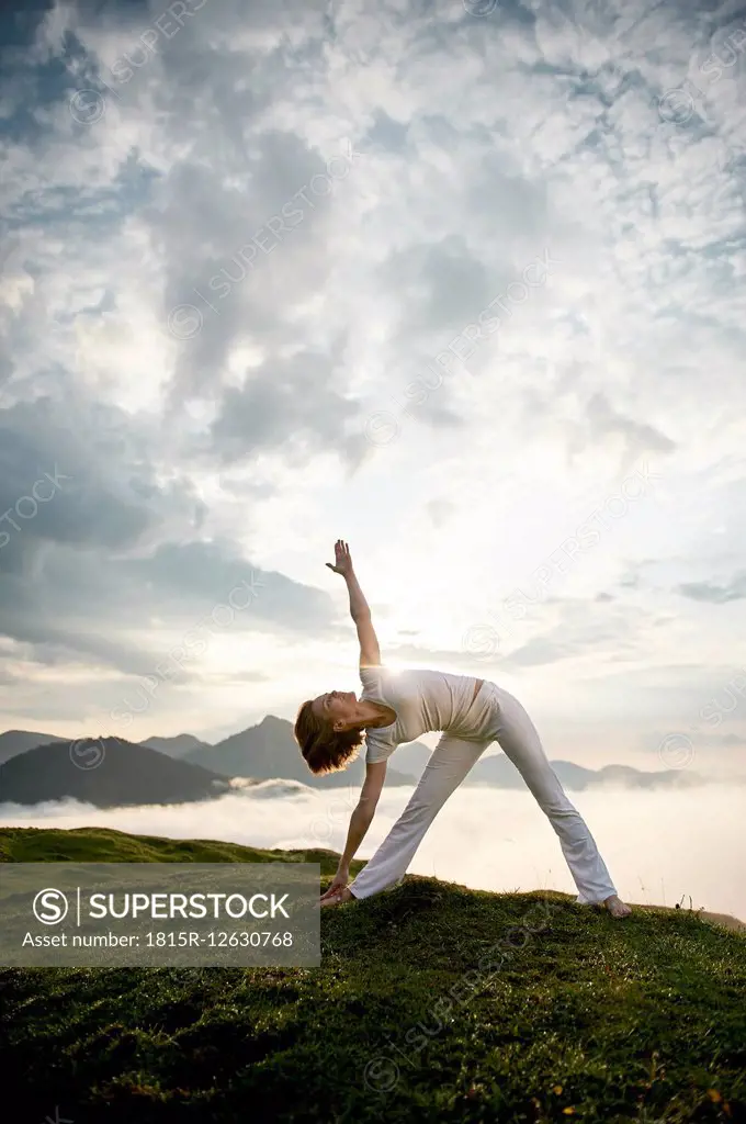 Austria.Kranzhorn, Mid adult woman practising yoga on mountain top