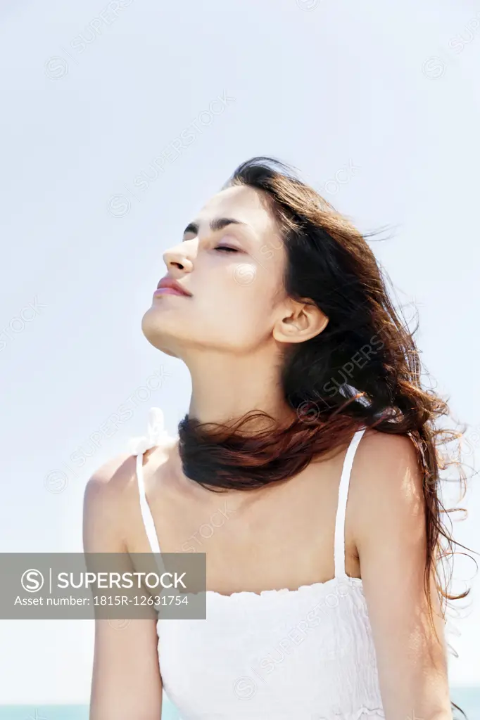 Brunette young woman with closed eyes enjoying sunshine