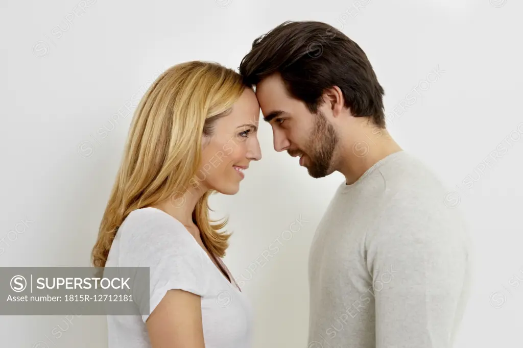 Happy couple in love looking at each other head to head in front of white background