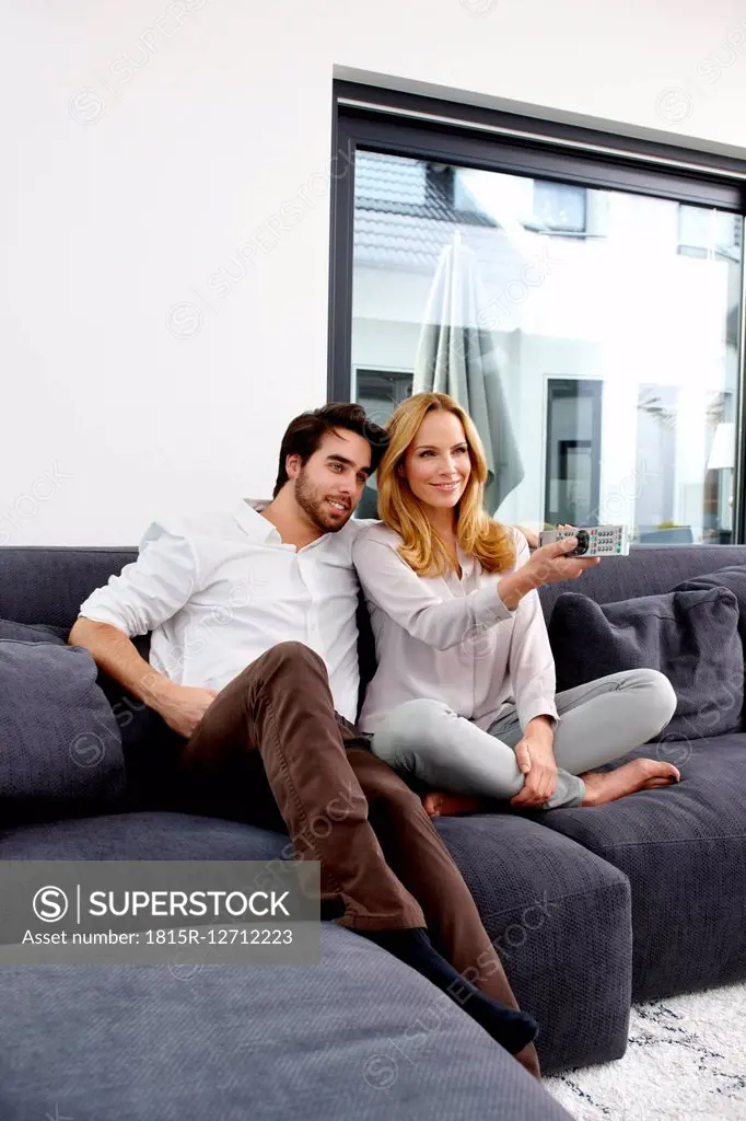 Couple sitting together on couch watching TV show