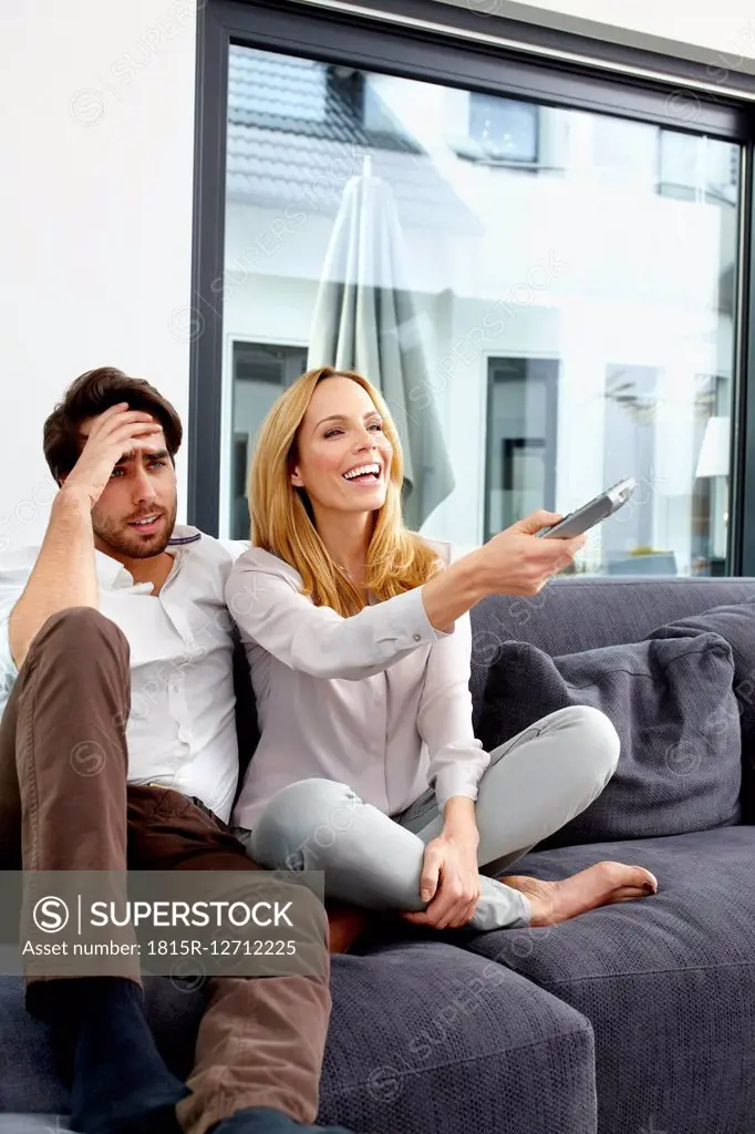Couple sitting together on couch watching TV show