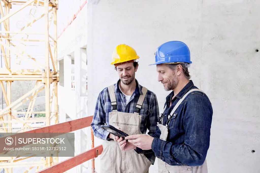 Two construction workers on construction site looking at digital tablet