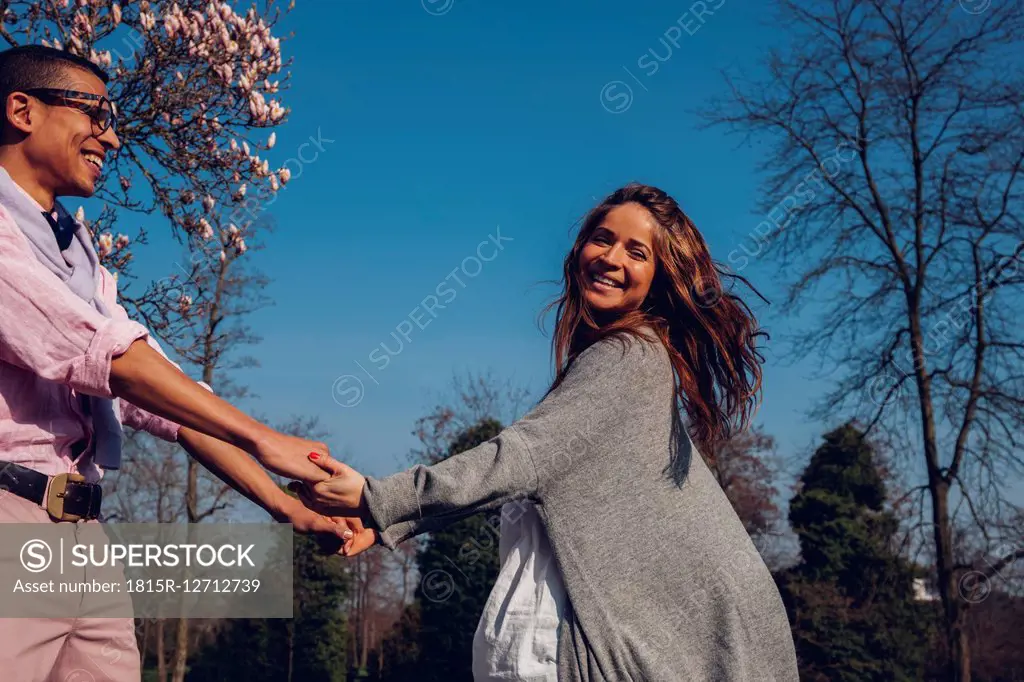 Happy young couple holding hands in park