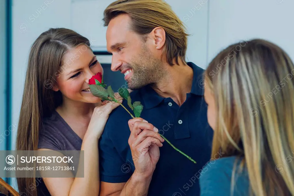 Smiling couple with red rose and daughter
