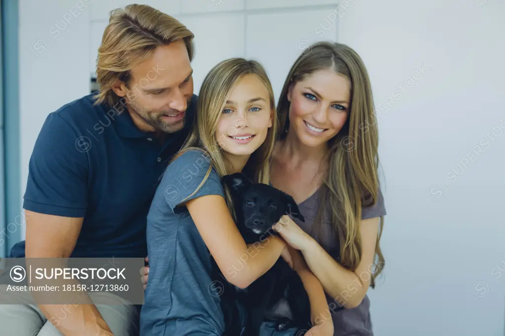 Portrait of smiling father, mother and daughter with puppy