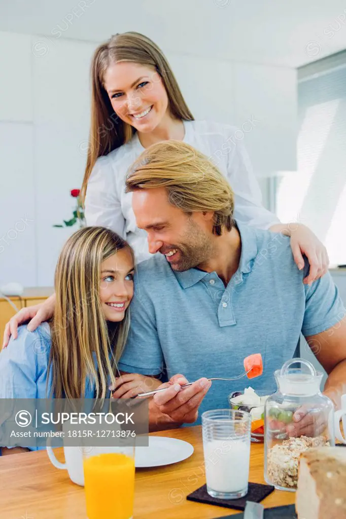 Happy mother, father and daughter at kitchen table