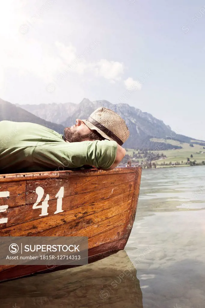 Austria, Tyrol, man relaxing on a boat on Walchsee