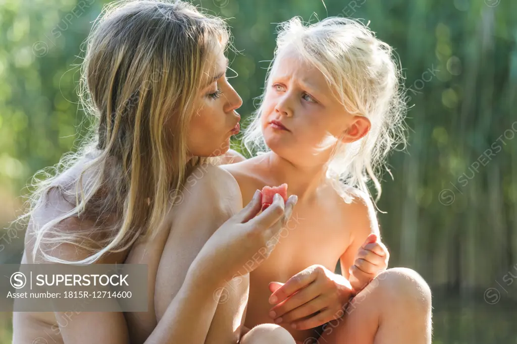 Mother and daughter sharing a piece of watermelon outdoors