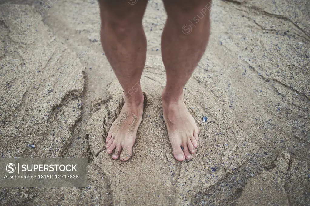 Man's bare feet in the sand on the beach