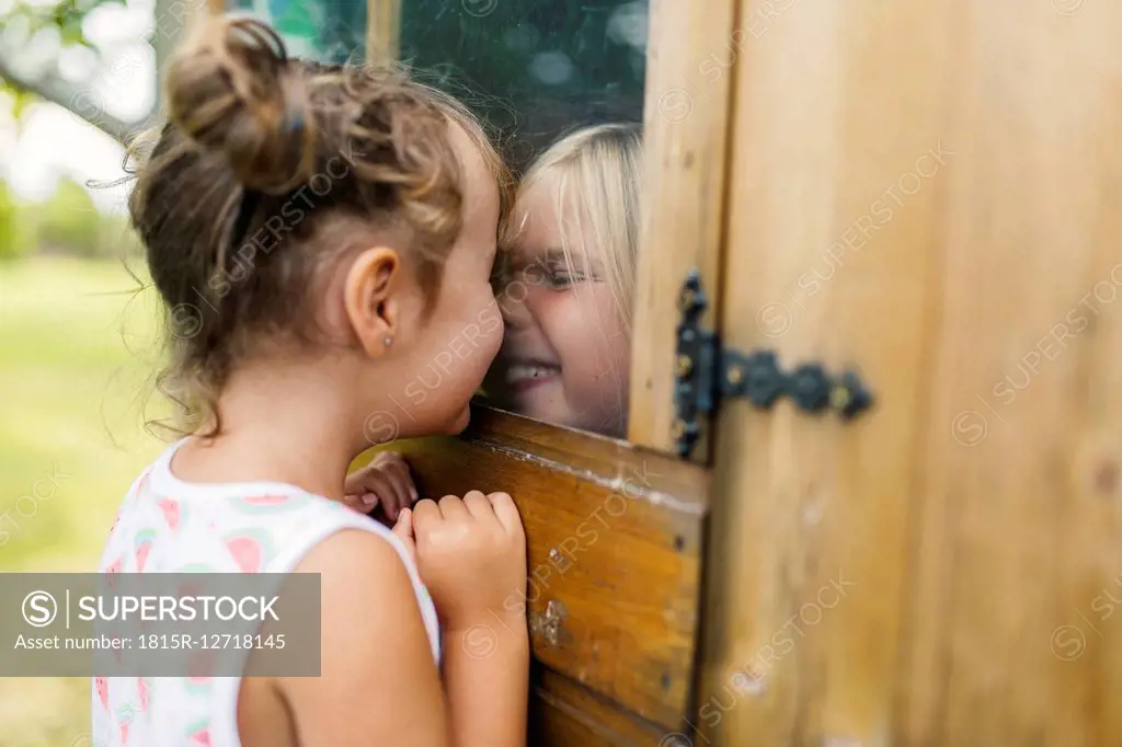 Spain, Asturias, Gijon, Little girls playing through a glass window